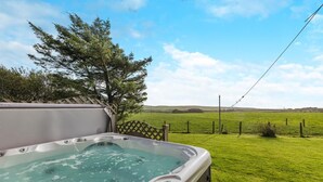 Ein Whirlpool mit freiem Blick auf ein grünes Feld und einen Baum im Hintergrund.