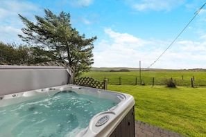 Ein Whirlpool mit freiem Blick auf ein grünes Feld und einen Baum im Hintergrund.