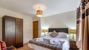 Ein Hotelzimmer mit einem Bett, zwei Nachttischlampen, einem Schrank, einem Sessel und einer Deckenleuchte.