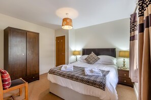 Ein Hotelzimmer mit einem Bett, zwei Nachttischlampen, einem Schrank, einem Sessel und einer Deckenleuchte.