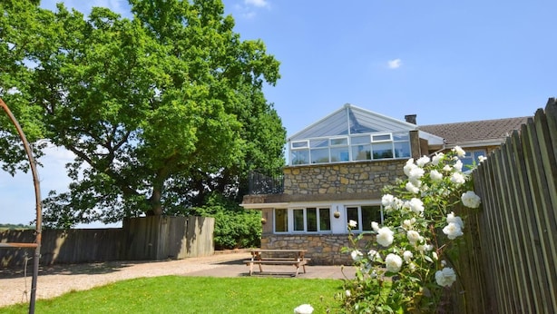 A house with a stone facade, a large tree, and a wooden fence. - 2 Bed in Cardiff (oc-45394) (Peterston-super-Ely)