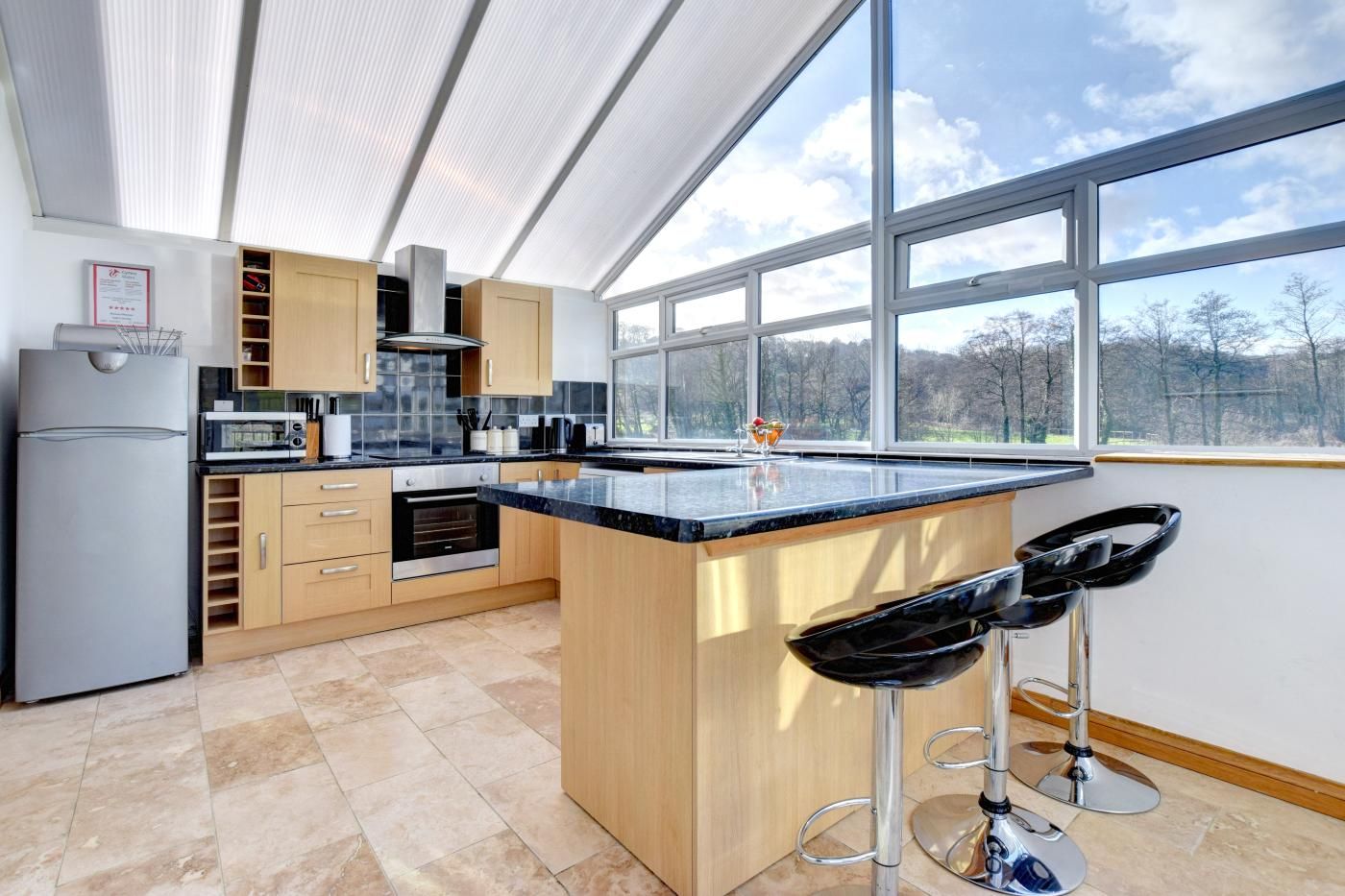 A modern kitchen with a large island, bar stools, and a view of the outdoors.