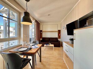 A compact hotel room with a dining table, a sofa, a small TV, and a kitchenette. - Perfekt fur 2 - Moderne Ferienwohnung Strandnah in Sellin (Sellin)