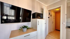 A compact kitchen with a microwave, a small refrigerator, and a flat-screen TV mounted on the wall. - Perfekt fur 2 - Moderne Ferienwohnung Strandnah in Sellin (Sellin)