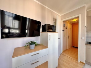 A compact kitchen with a microwave, a small refrigerator, and a flat-screen TV mounted on the wall. - Perfekt fur 2 - Moderne Ferienwohnung Strandnah in Sellin (Sellin)