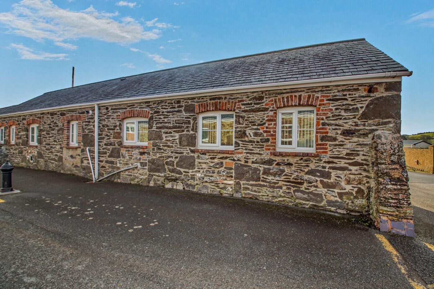 A stone building with a sloped roof and multiple windows.