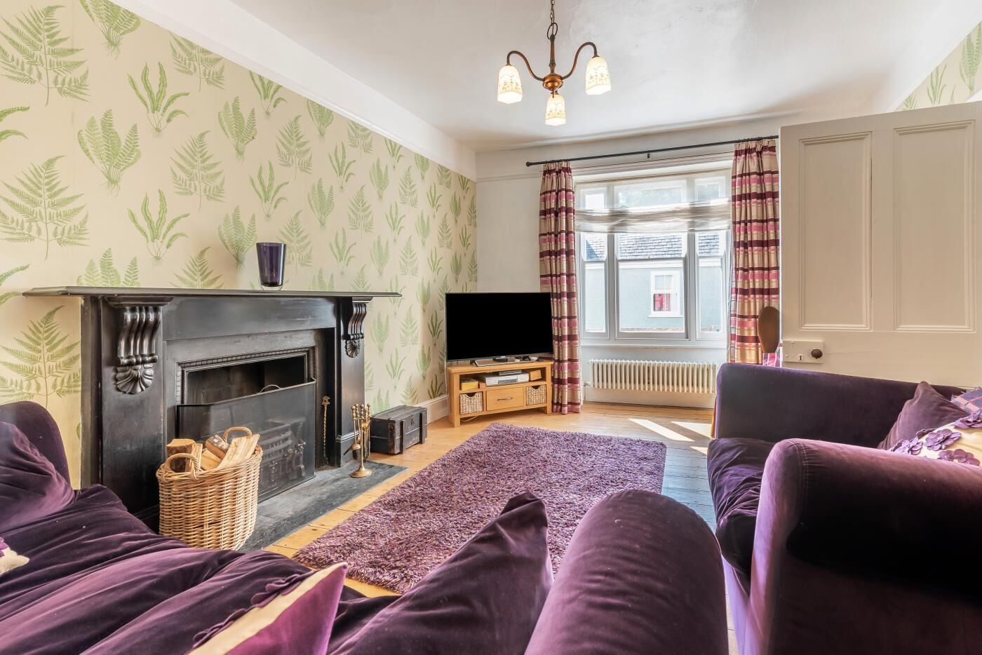 Ein Wohnzimmer mit Kamin, Fernseher und violetten Möbeln.