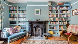 Una sala de estar acogedora con chimenea, estanterías, un sofá y un tapete estampado.