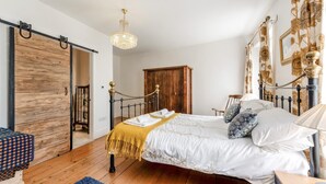 Un dormitorio con cama, armario de madera, candelabro y alfombra azul.