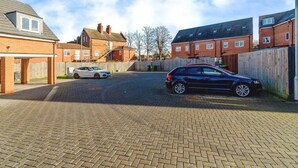 Een woonstraat met huizen, een verharde oprit en geparkeerde auto's.