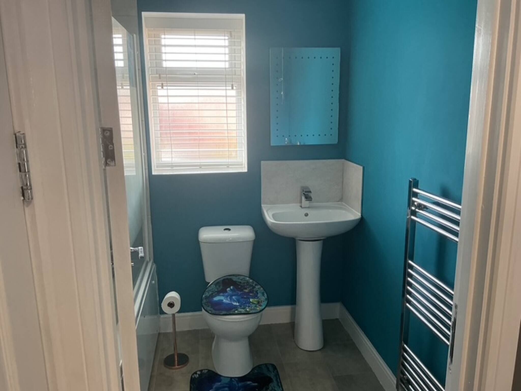 Un bagno con il water, un lavandino e una finestra con persiane.