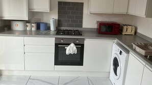 Een keuken met een fornuis, oven, magnetron en een wasmachine.