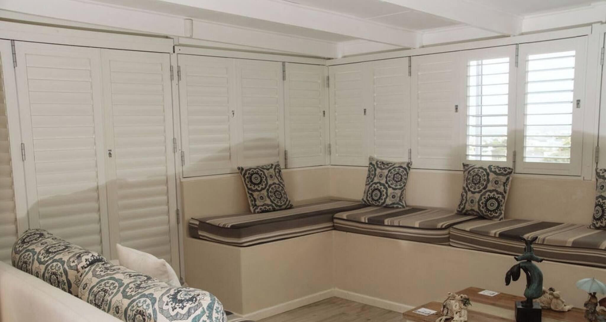 A room with a built-in bench seating area, a sofa, and a small table with decorative items.