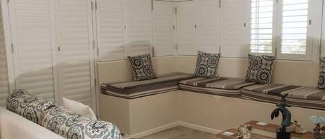A room with a built-in bench seating area, a sofa, and a small table with decorative items.