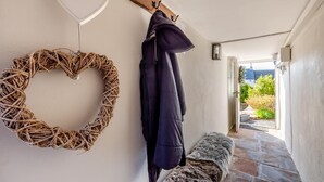 A hallway with a heart-shaped wicker wreath, a coat rack with a jacket, a bench, and a view of the outdoors. - 2 Bed in Long Marton (oc-c34661) (Long Marton)