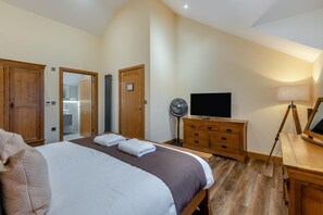 Ein Hotelzimmer mit einem Bett, einem Holzschrank, einem Fernseher, einem Nachttisch, einer Lampe und einem Spiegel.