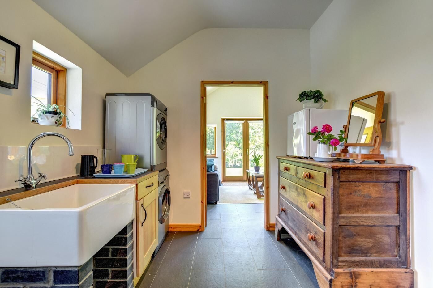 Une cuisine équipée d’un évier, d’un lave-linge et de meubles de rangement en bois.