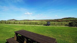 Een picknicktafel in een grasveld met een hek en een bord op de achtergrond.