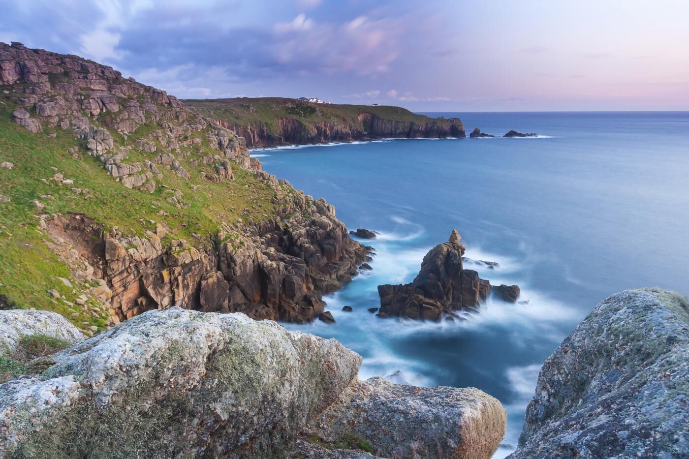 A coastal landscape with rocky cliffs and a view of the ocean.