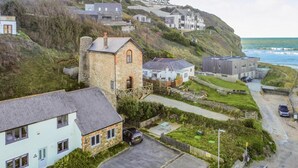 Ett bostadsområde vid kusten med hus, en byggnad av sten och utsikt över havet.