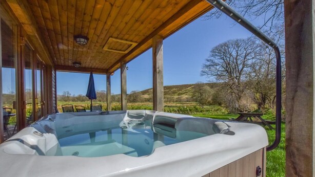 A hot tub under a wooden pergola with a clear view of the surrounding landscape. - 2 Bed in Llandrindod Wells (oc-510531) (Llanbister)