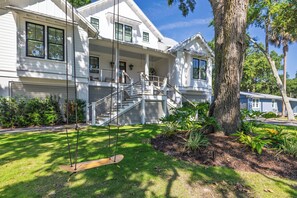 A two-story house with a porch, a swing, and a tree. - Stay @ Isle of Coladas (Isle of Palms)