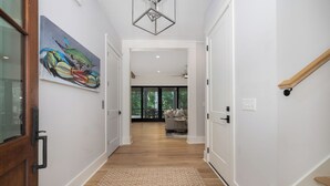 A hallway with a wooden floor, a rug, a painting, and a staircase. - Stay @ Isle of Coladas (Isle of Palms)