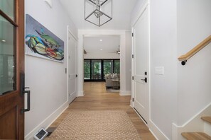 A hallway with a wooden floor, a rug, a painting, and a staircase. - Stay @ Isle of Coladas (Isle of Palms)