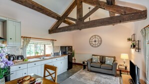 A cozy kitchen with a dining area, a living room with a sofa and TV, and exposed wooden beams. - 1 Bed in Welshpool (oc-381818) (Welshpool)