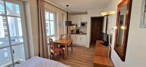 A hotel room with a bed, a dining table with chairs, a kitchenette, and a TV. - Ostseeurlaub fur 2 - Ferienwohnung in Sellin mit Balkon (Sellin)