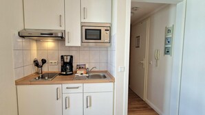 Eine kleine Küche mit Mikrowelle, Kaffeemaschine und Spüle.