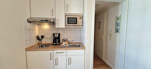 A compact kitchen with a microwave, coffee maker, and a sink. - Ostseeurlaub fur 2 - Ferienwohnung in Sellin mit Balkon (Sellin)