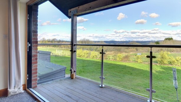 Ein Balkon mit Metallgeländer, der auf eine Wiese und einen klaren Himmel blickt.