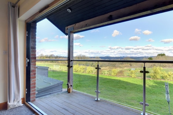 Ein Balkon mit Metallgeländer, der auf eine Wiese und einen klaren Himmel blickt.