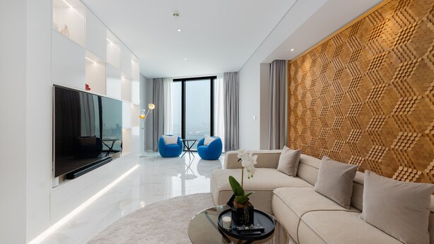 A modern living room with a flat-screen TV, a sofa, a coffee table, and a decorative wall panel. - Address JBR 3BR Direct Beach Ain Dubai View (Dubai)