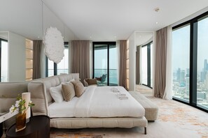 Ein modernes Schlafzimmer mit einem großen Bett, einer Sitzecke und Blick auf die Stadt.