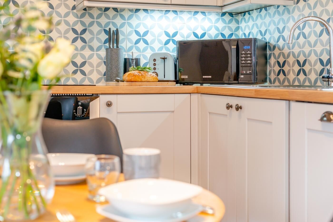 Une cuisine moderne équipée d’un four à micro-ondes, d’un grille-pain et d’un vase de fleurs posé sur le plan de travail.