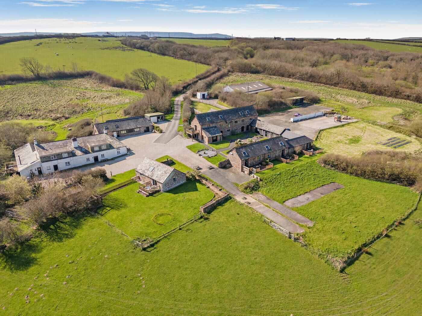 A rural farmstead with stone buildings, a central courtyard, and surrounding fields.