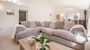 Un salon moderne avec un canapé d’angle, une table basse et une plante en pot.