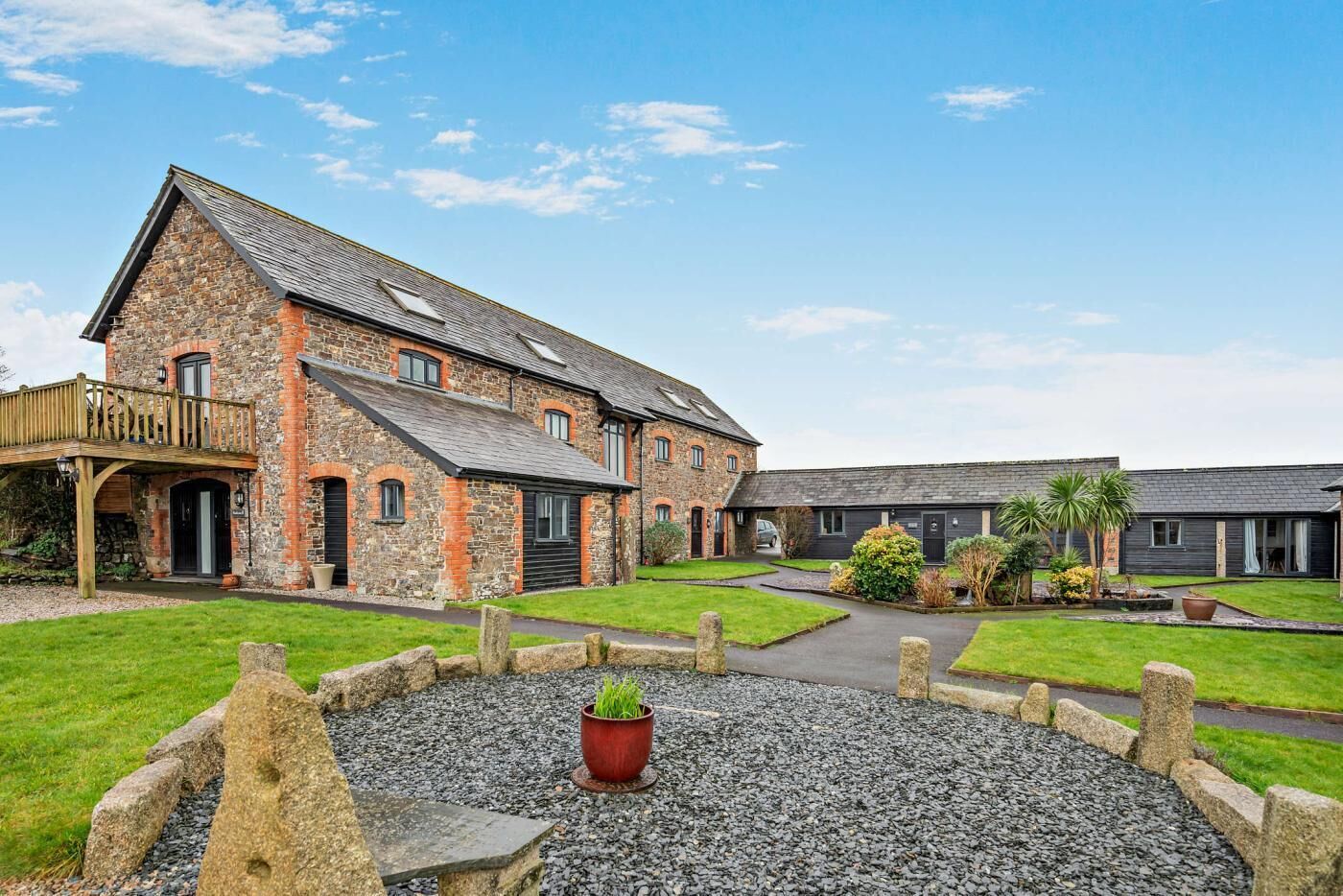 A stone building with a wooden deck and a gravel courtyard.