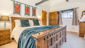 Ein Schlafzimmer mit einem hölzernen Bett, einem Nachttisch, einer Kommode und einem Fenster mit Vorhängen.