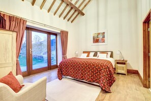 A bedroom with a bed, a chair, a nightstand, a painting, and a view through a glass door. - 4 Bed in Menai Bridge (oc-bow16) (Menai Bridge)