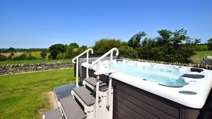 Ein Whirlpool mit Stufen und Geländern, umgeben von einer Steinmauer und Pflanzen.