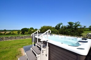 A hot tub with steps and railings, surrounded by a stone wall and greenery. - 4 Bed in Menai Bridge (oc-bow16) (Menai Bridge)