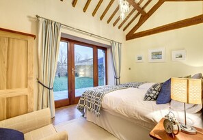 A bedroom with a bed, a nightstand with a lamp, a chair, and a view of the outdoors through a glass door. - 4 Bed in Menai Bridge (oc-bow16) (Menai Bridge)