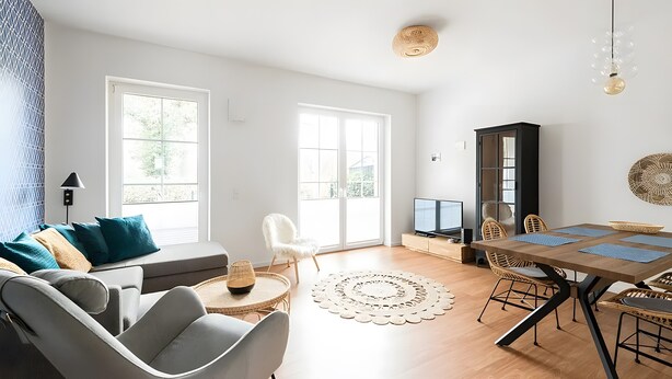 Een moderne woonkamer met een bank, stoelen, een eettafel en een televisie.