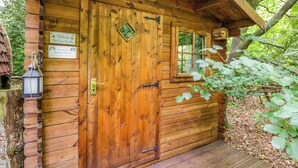 A wooden cabin with a door, a window, and a sign indicating it is for the Daisy Pod's use. - Daisy Glamping Pod (Newbury)
