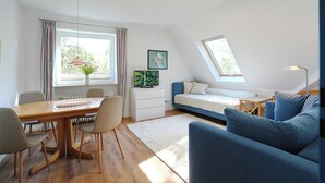 Et moderne loftrum med spiseplads, sofa, lille bord og seng.