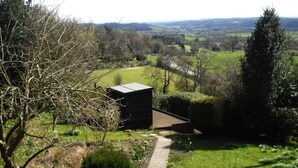 Un paisaje rural con un edificio pequeño, un sendero y vistas al campo.
