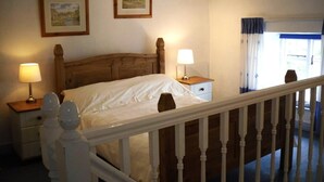 Un dormitorio con una cama de madera, dos lámparas de noche, una mesita de noche y dos cuadros en la pared.
